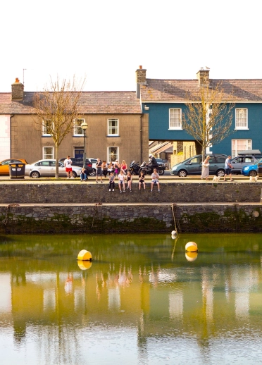 people sat on wall, Aberaeron harbour.