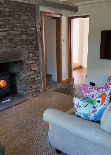 Living room in a cottage with a fireplace, large sofa and table.