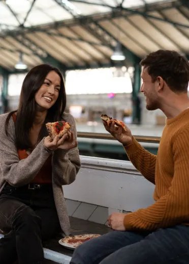 A couple enjoying pizza on a market terrace