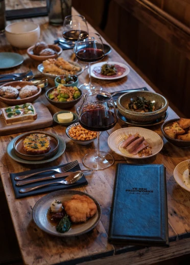 wooden table with tapas dishes and glasses of red wine.