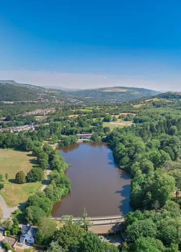 Aeriel view of a country park including a lake, woodland and green space.