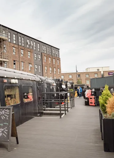 Old railway carriages in a yard converted into cafes and shops.