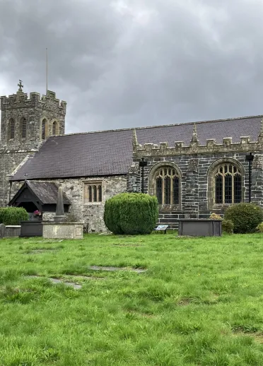 A stone-built church with a tower in a graveyard.