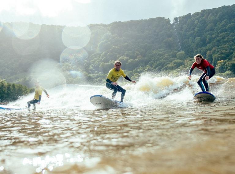 3 people surfing on a lagoon.