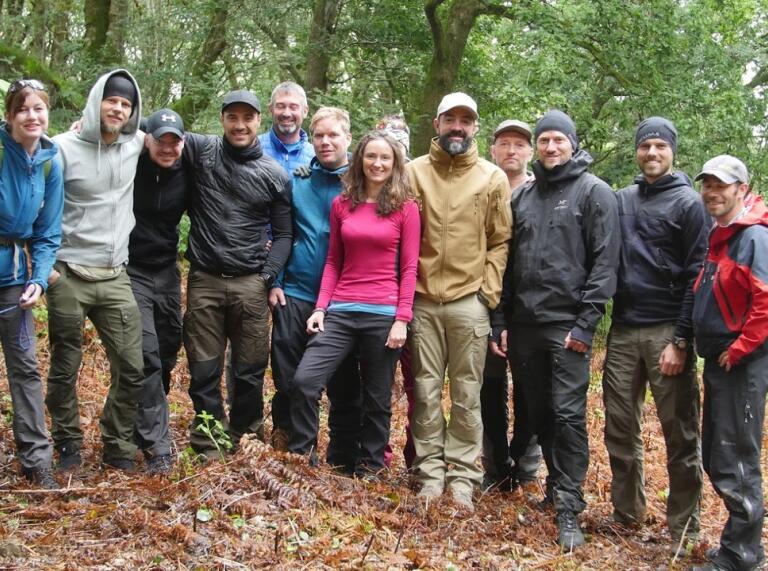 Claire Copeman with a group of clients in a forest smiling at the camera.