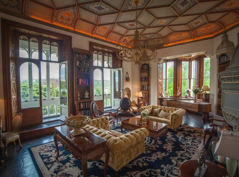 An elegant lounge area with ornate ceiling, large windows and patio doors.