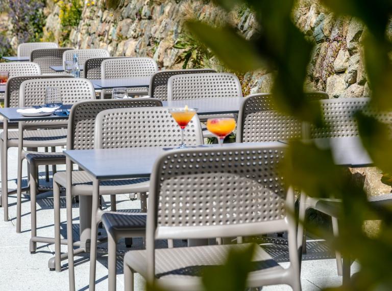 Dining tables and chairs on an outside terrace in a hotel restaurant.