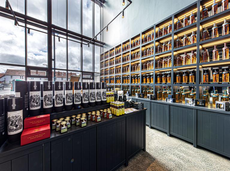 Shelves filled with whisky products in a shop which has large glass fronted windows.