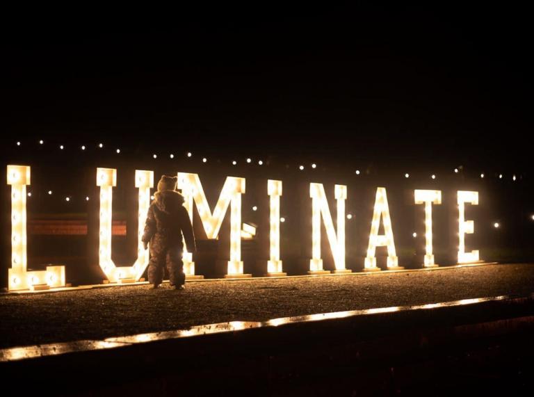 Light up Luminate sign with a small child standing by it