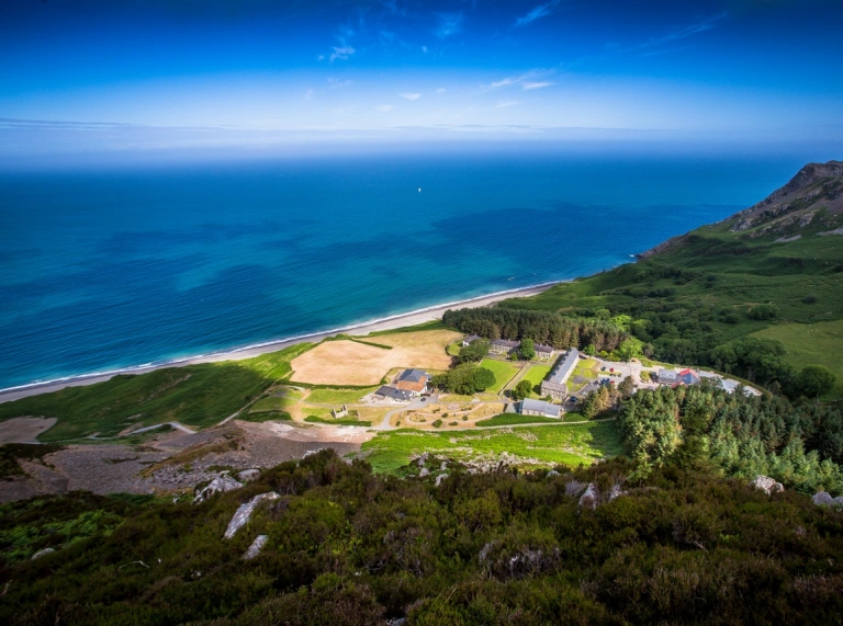 Aerial shot of a Welsh language cultural centre surrounded by sea and mountains.