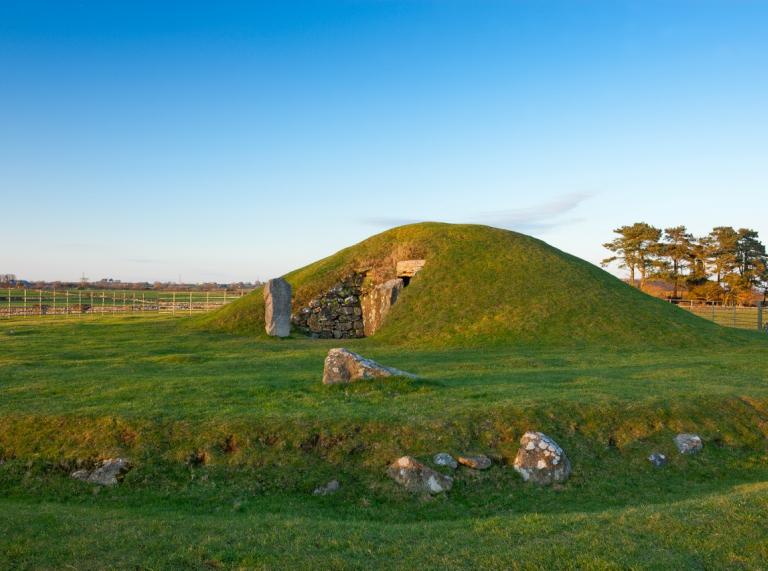 A green mound with an entrance made of stone leading into a burial chamber.