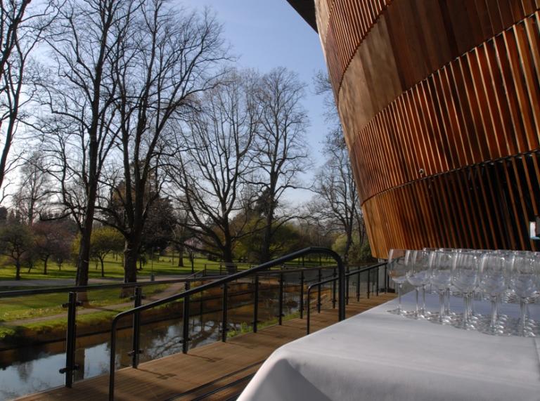 Drinks laid on a table outside a building with views of the river and greenery.