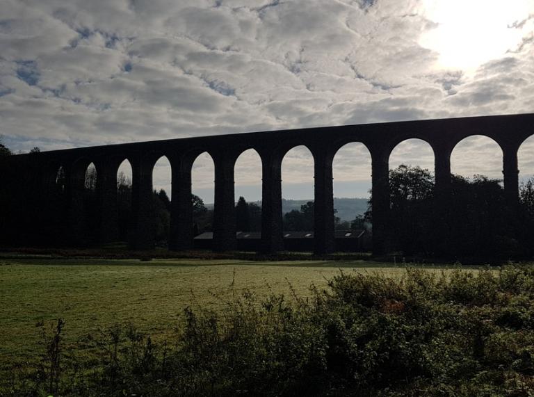 Silhouette of a huge viaduct crossing a valley with fields in foreground