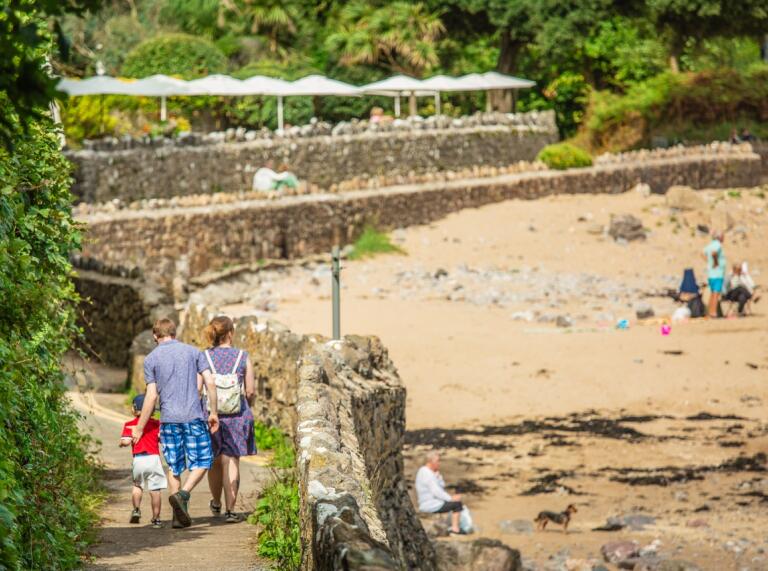 Family walking down path beside the beach with hotel garden in background
