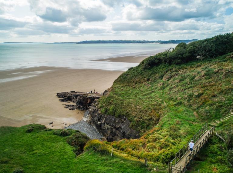 Blick auf Meer und Sand von einer Klippe auf dem Wales Coast Path.