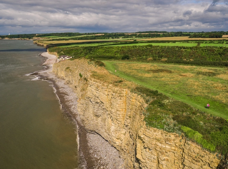 Menschen, die auf einem Küstenwanderweg hoch über den Klippen und dem Meer wandern.
