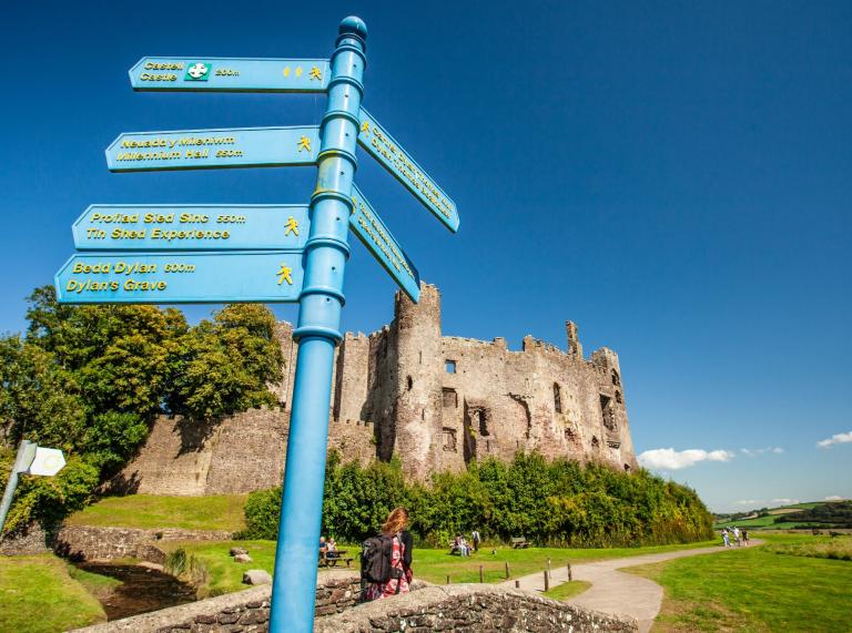 Laugharne Castle with a signpost directing visitors to other attractions.