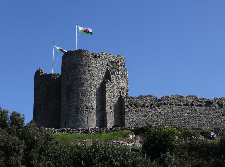 Criccieth Castle on a hill with two Welsh flags waving