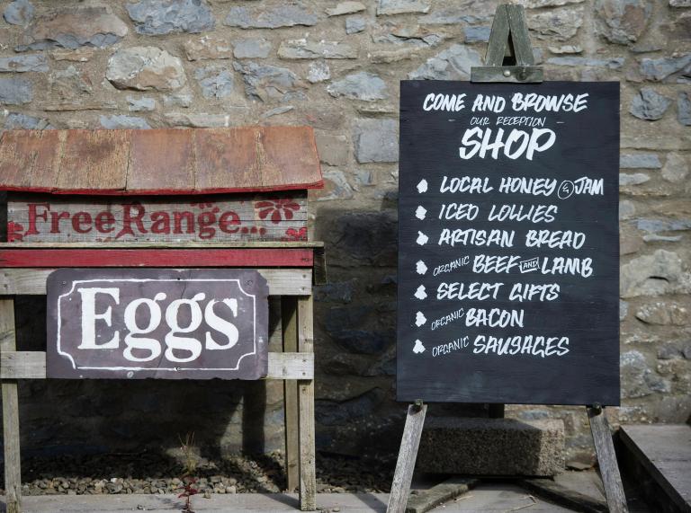 Sign for a farm shop promoting eggs and other produce.