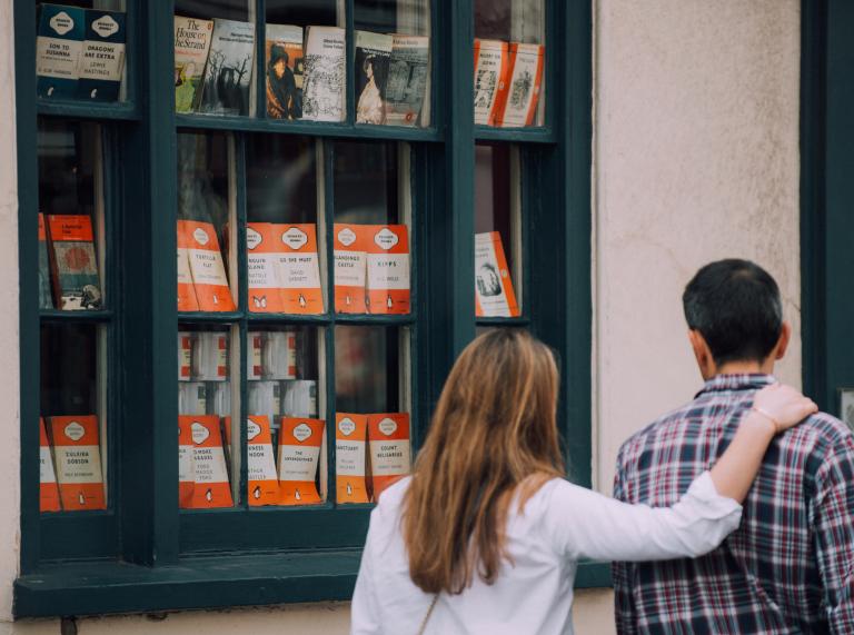 Eine Frau und ein Mann schauen durch das Fenster einer Buchhandlung.
