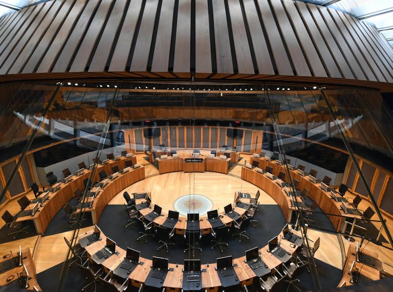 Stühle und Tische in einem Kreis im Plenarsaal des Parlamentsgebäudes.