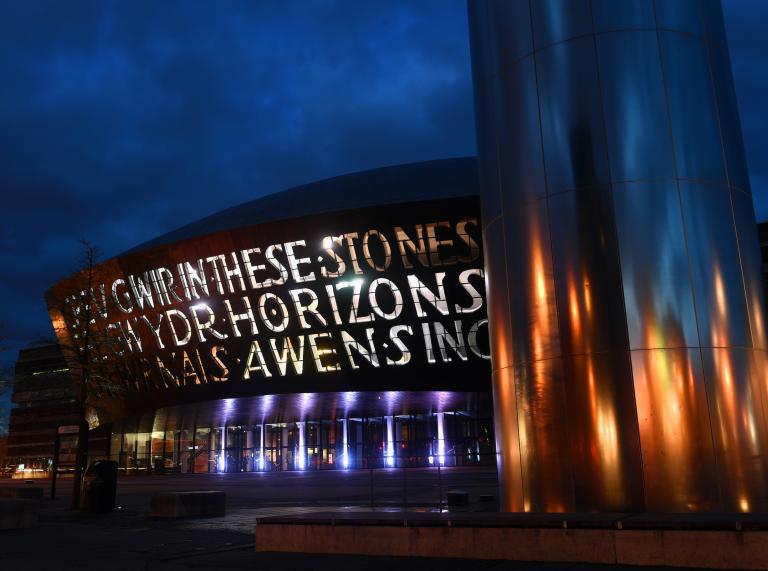 Exterior shot of Wales Millennium Centre lit up at night.