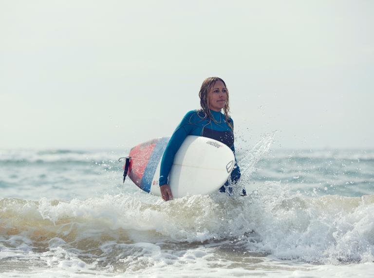 Kirsty Jones with surfboard in the sea