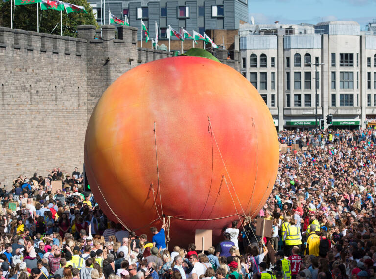 A giant inflatable peach and crowds by the castle in Cardiff.