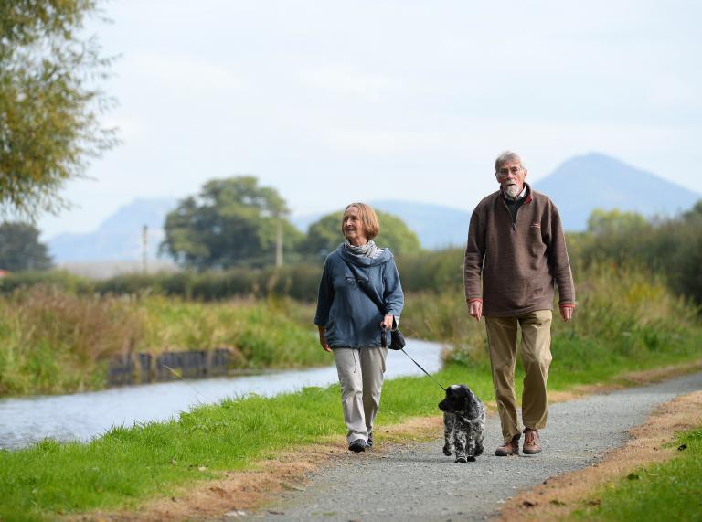 Ein Paar geht mit Hund auf dem Glyndŵr's Way spazieren.