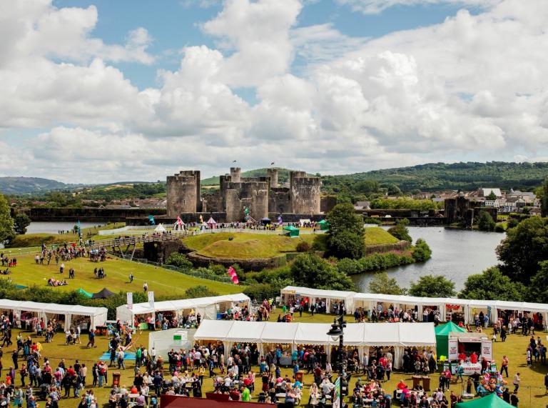 Crowds of people at stalls on a sunny day with the castle in the background.