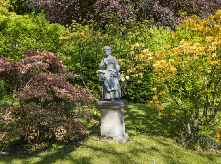 Colby Woodland Garden showing a statue surrounded by rhododendrons.  