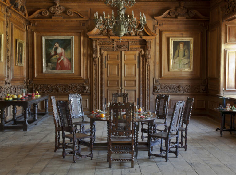 Speisesaal mit Holzvertäfelung und Wandmalereien, Kronleuchter, Holztisch und Stühlen
