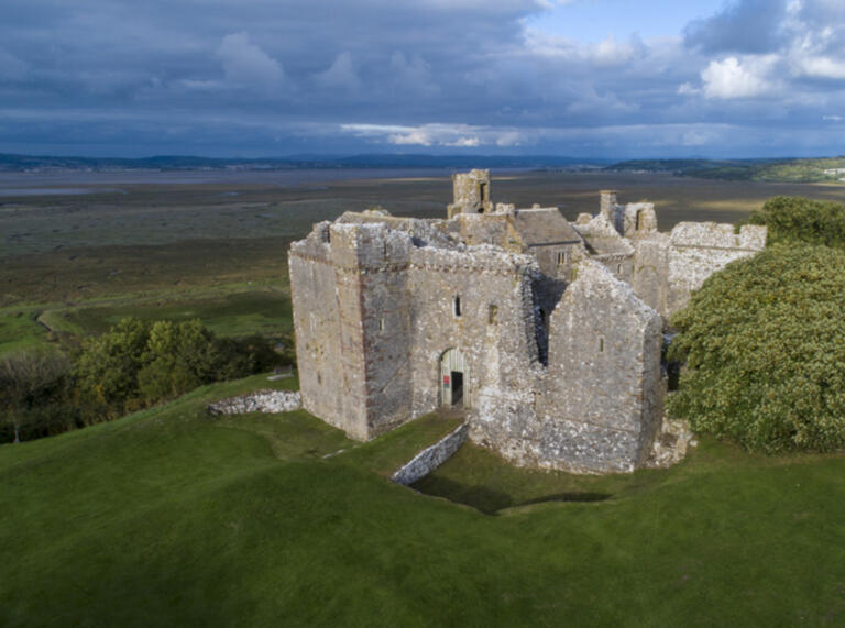 aerial shot looking down on castle with grass and coast beyond 