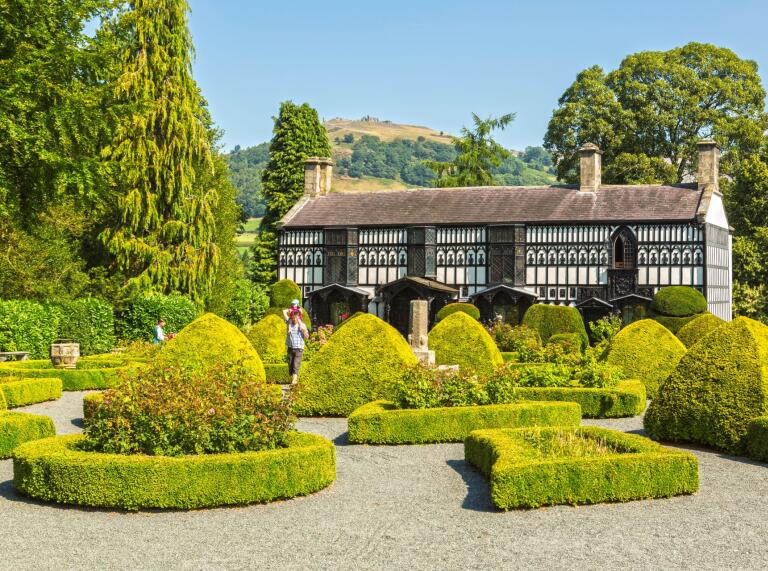 Plas Newydd house behind the gravelled courtyard and manicured hedges and trees.
