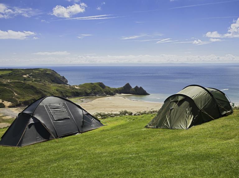 Zelte im Three Cliffs Bay Holiday Park auf der Halbinsel Gower mit Blick auf den Strand.