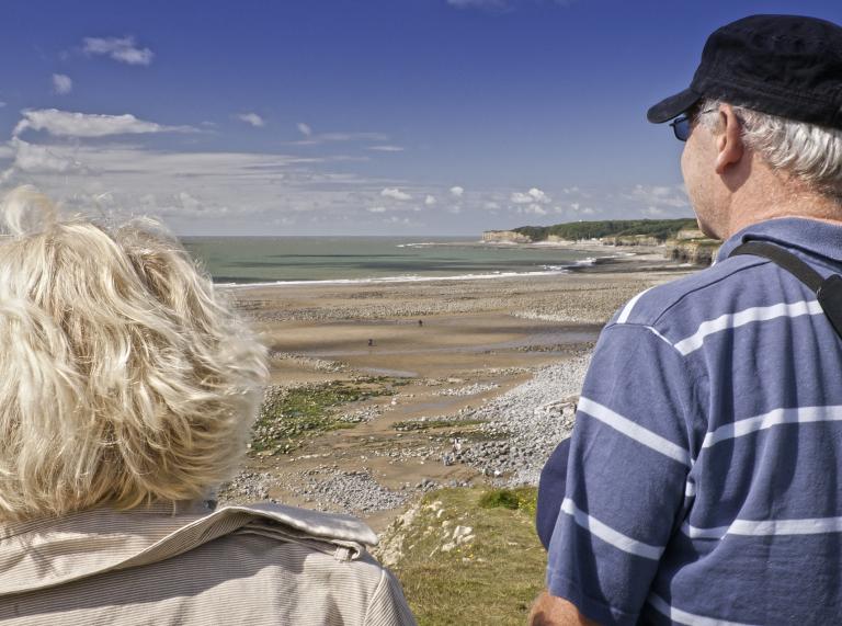 Two people looking out over a beach.