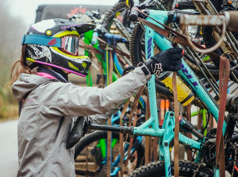 A mountain biker with a helmet on looking at a rack of bikes.