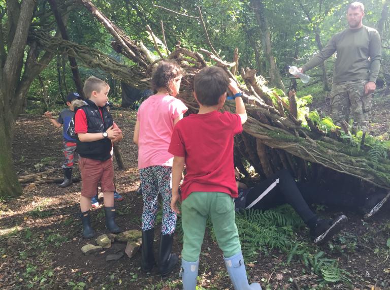 Young children building a shelter from wood.
