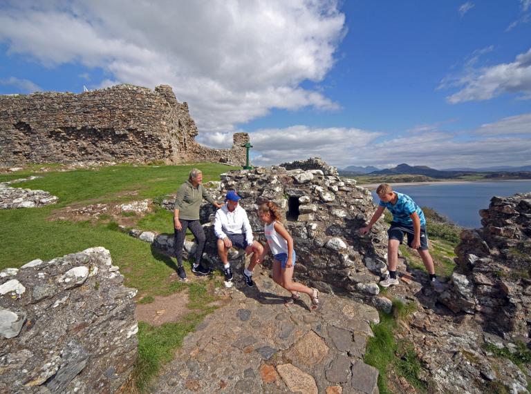Zwei Erwachsene und zwei Kinder erkunden Criccieth Castle.
