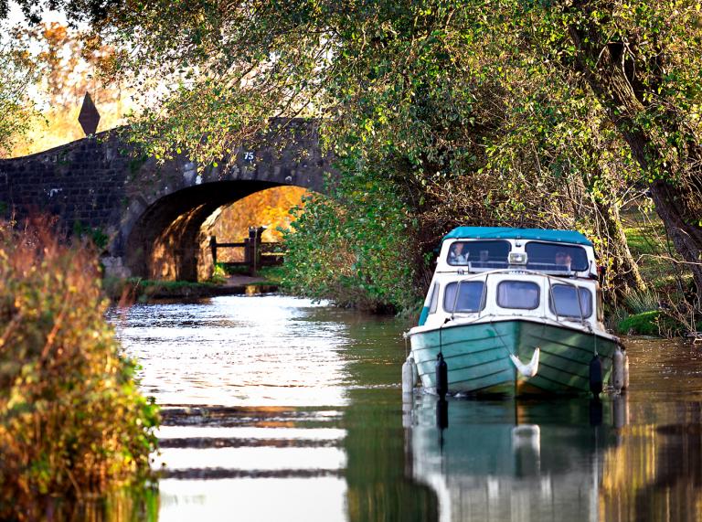Ein Boot auf einem Kanal mit einer Brücke im Hintergrund.