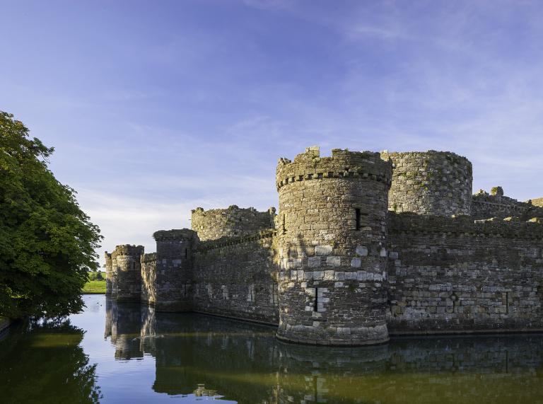 Seitenansicht von Beaumaris Castle mit Wasser und blauem Himmel.