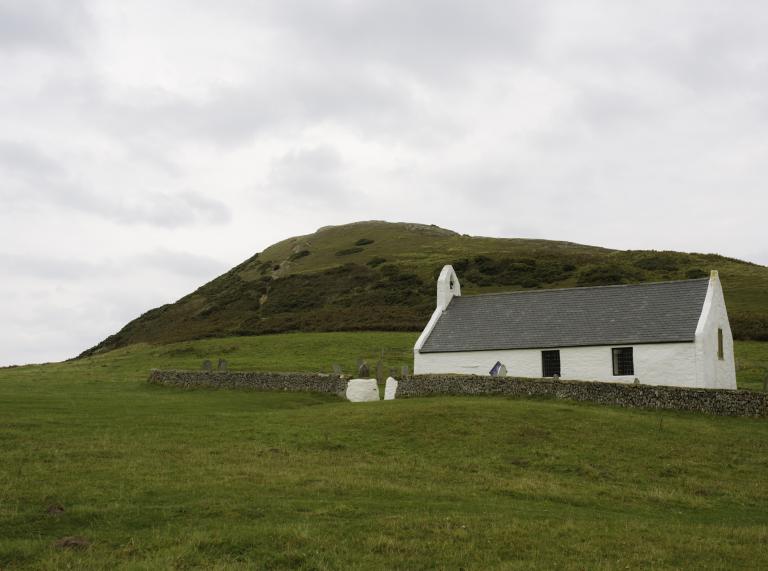 exterior of white stonewashed church with surrounding countryside.