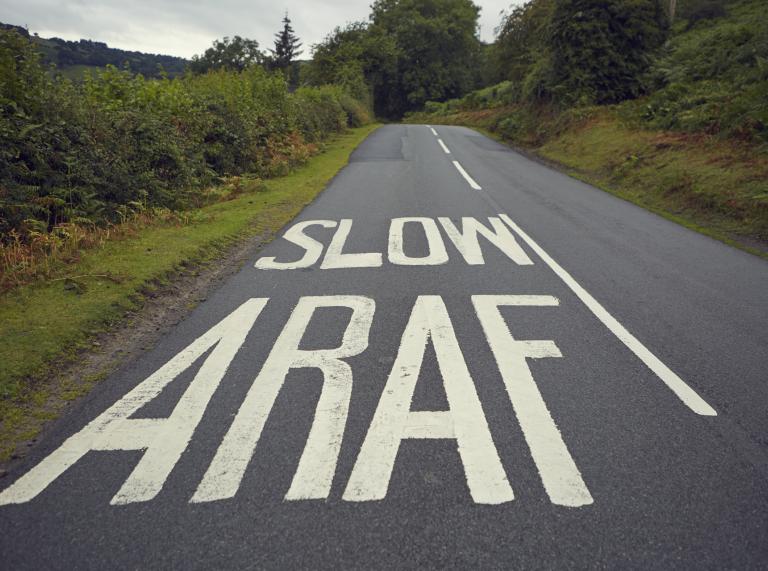 Aufgemalte Straßenmarkierung mit den Worten ‚slow‘ und ‚araf‘.