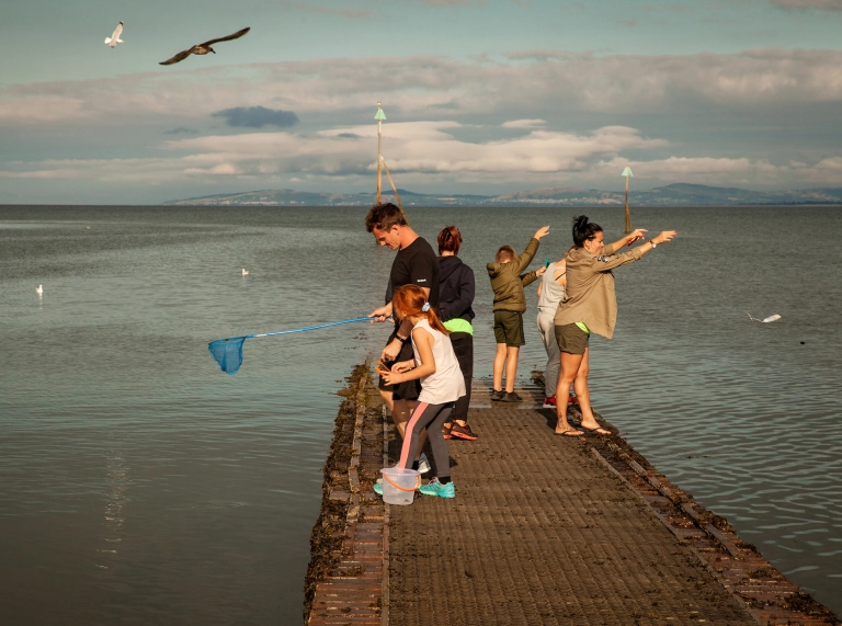 People crabbing off a small seaside jetty.