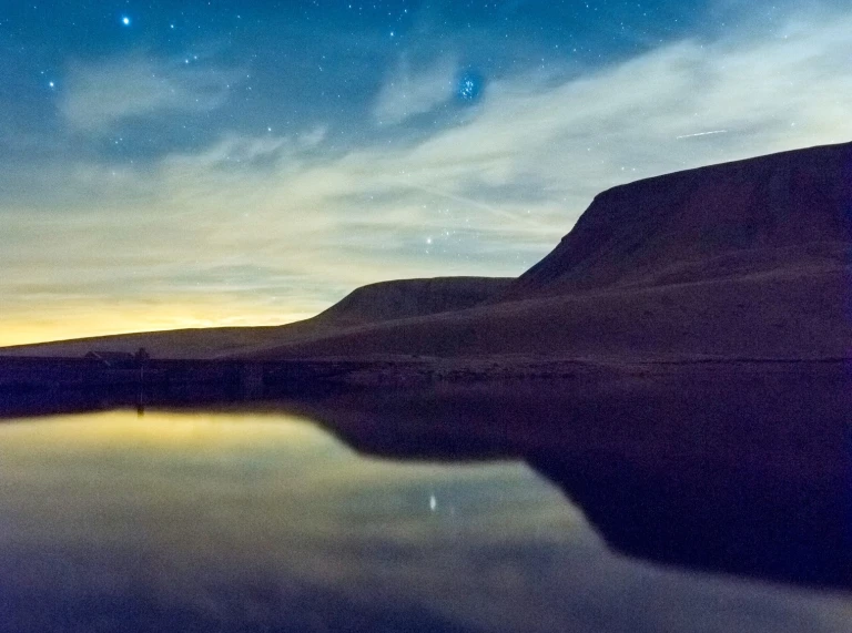 Mountain silhouetted against a starry sky captured in the Brecon Beacons.