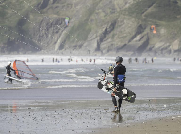 Kite-Surfer, die mit ihren Boards den Strand entlanglaufen