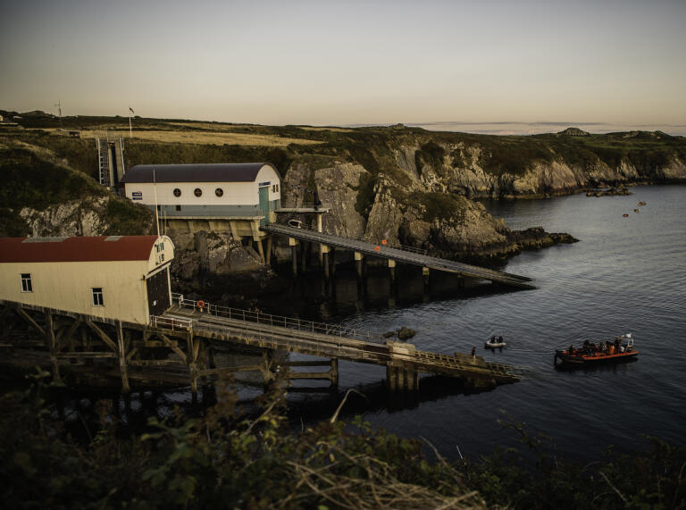 Two lifeboat launching buildings at sunset.