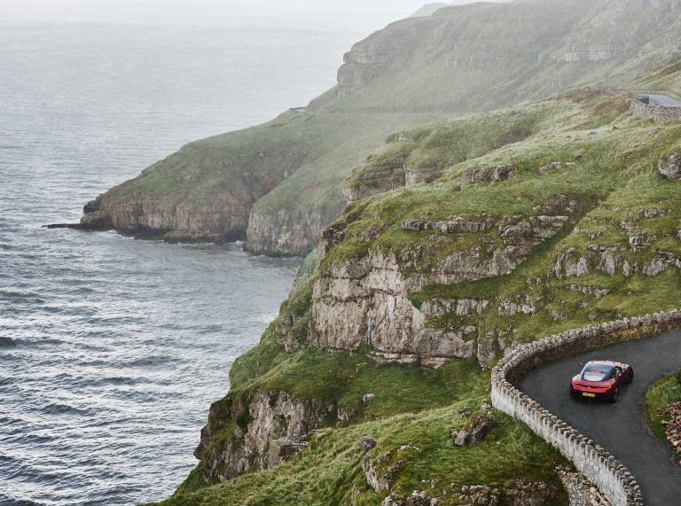 Car driving along a windy road on the Great Orme with the sea on the left hand side