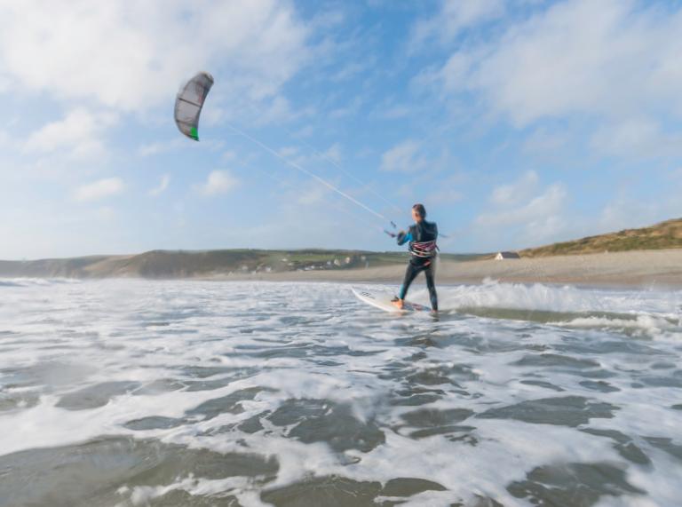 A man kitesurfing at Newgale beach with sand in distance