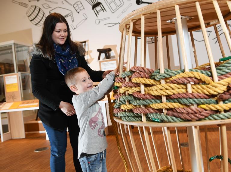 woman and boy in museum with exhibit with ropes.